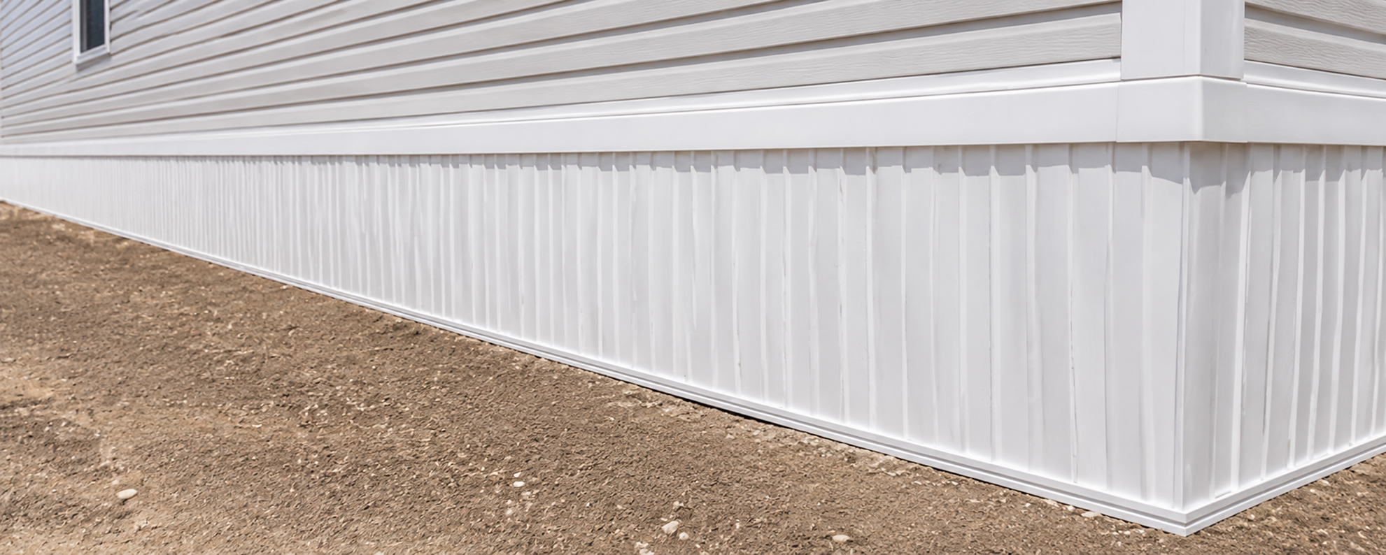 Newly installed white skirting along the base of a manufactured home